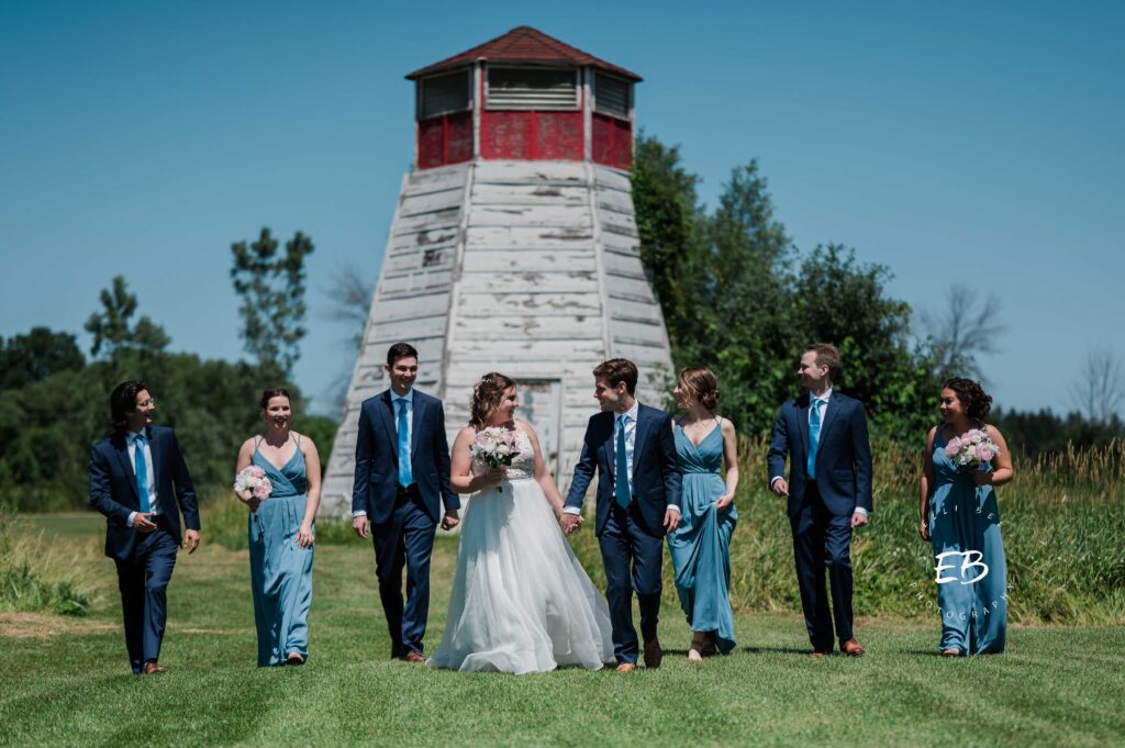 bride and groom with wedding party walking in front of a lighthouse