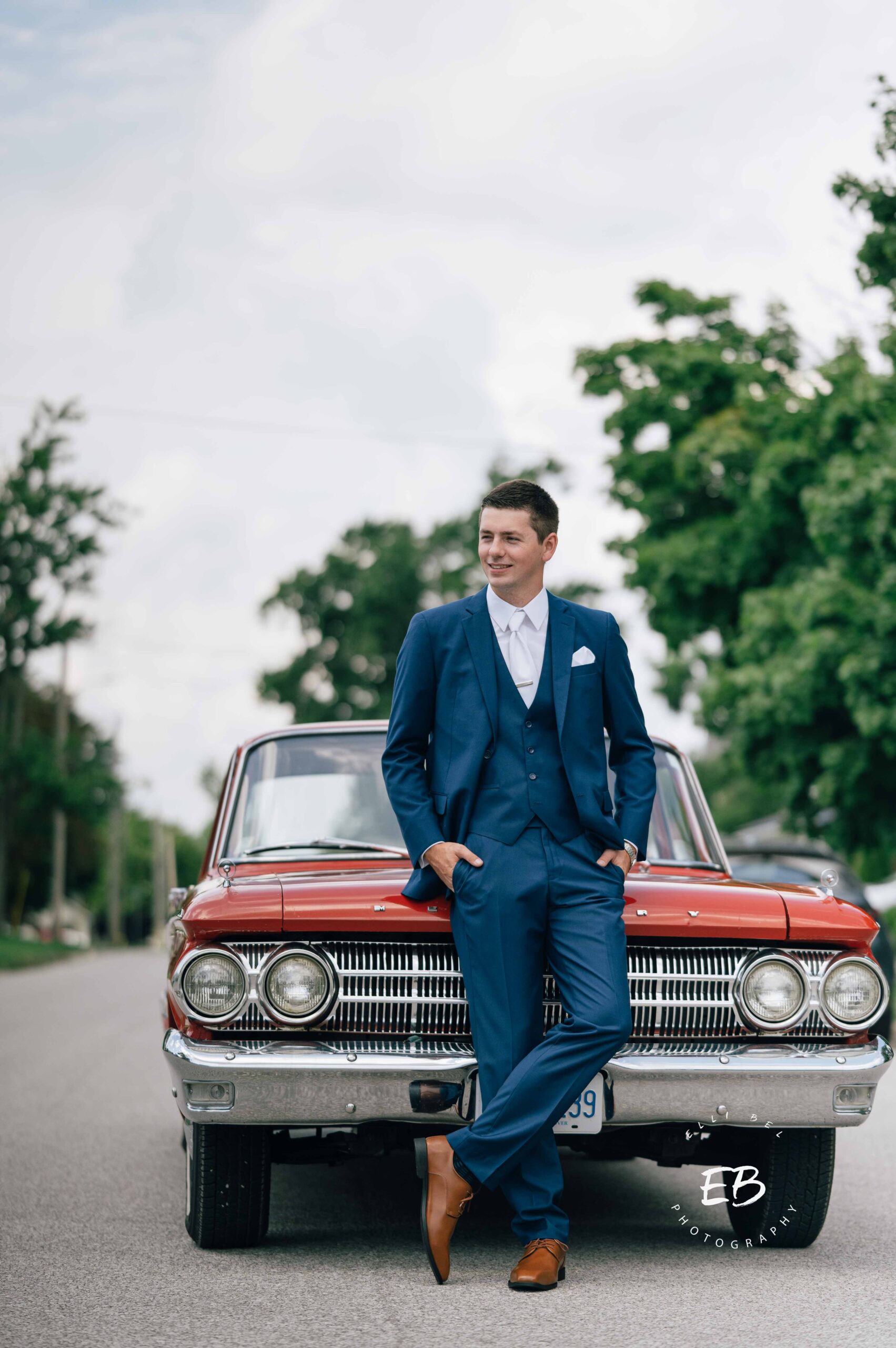 groom in front of a red sports car